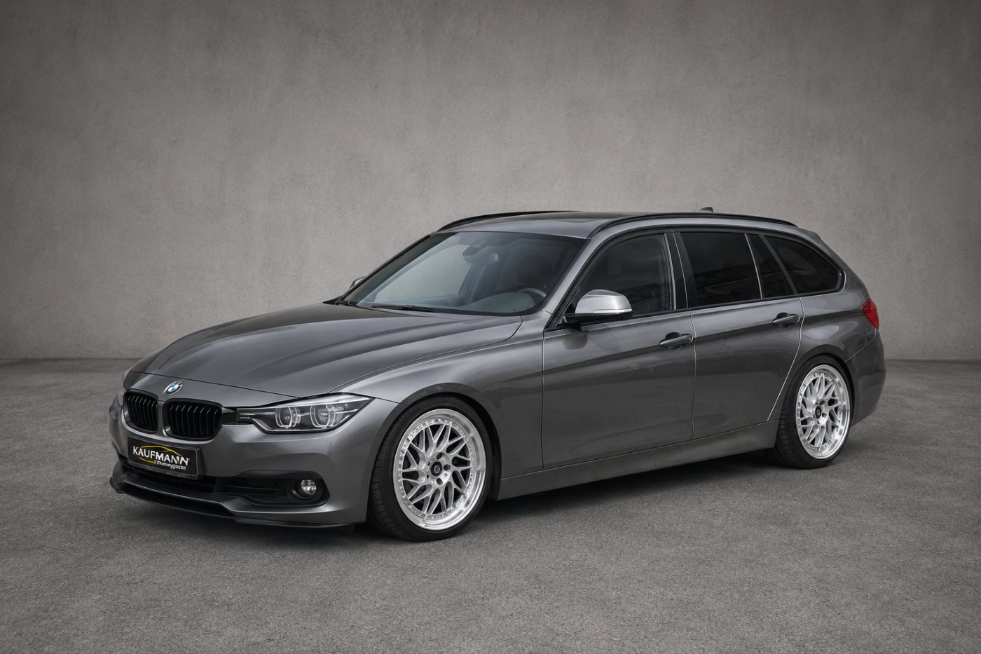 Grauer BMW 3er Touring mit silbernen Mehrspeichenfelgen und Kaufmann-Motorsport-Kennzeichenhalter