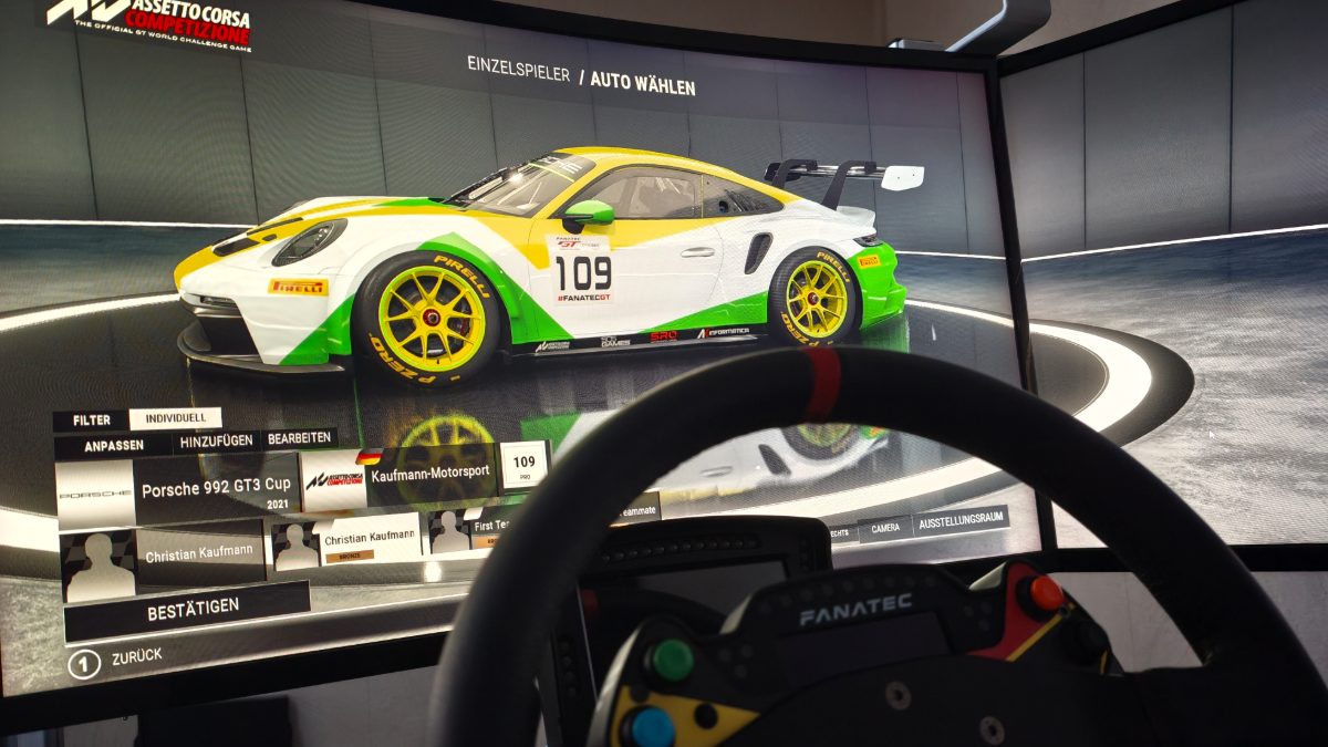 Das SimRacing-Rig mit Fanatec-Lenkrad vor dem gebogenen Bildschirm, im Spiel ein Fahrzeug in den Farben von Kaufmann Motorsport