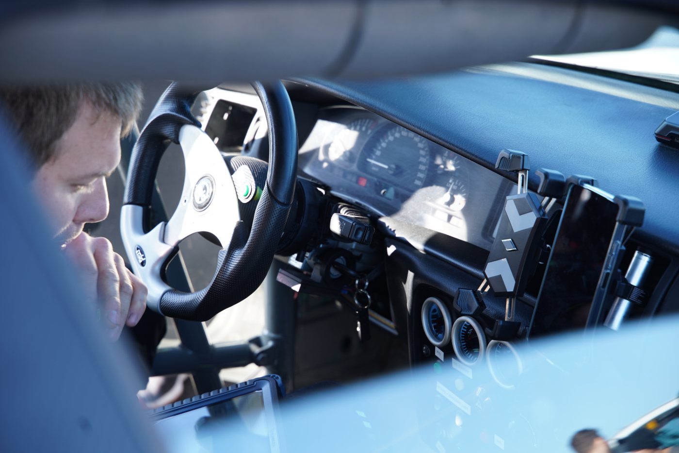 Blick durch das Seitenfenster auf das Cockpit mit Sportlenkrad, Instrumenten und Halterungen